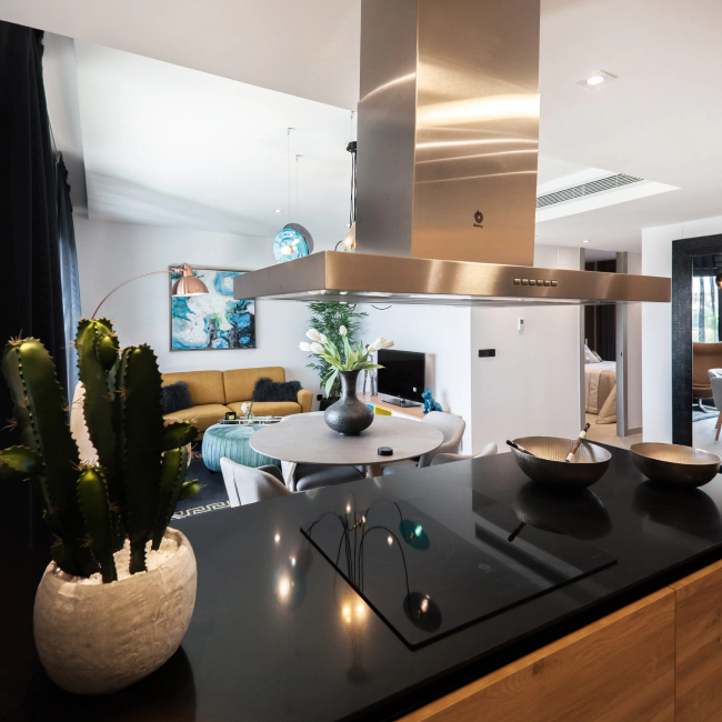 black countertop of a kitchen with a dining table and a yellow sofa at the back