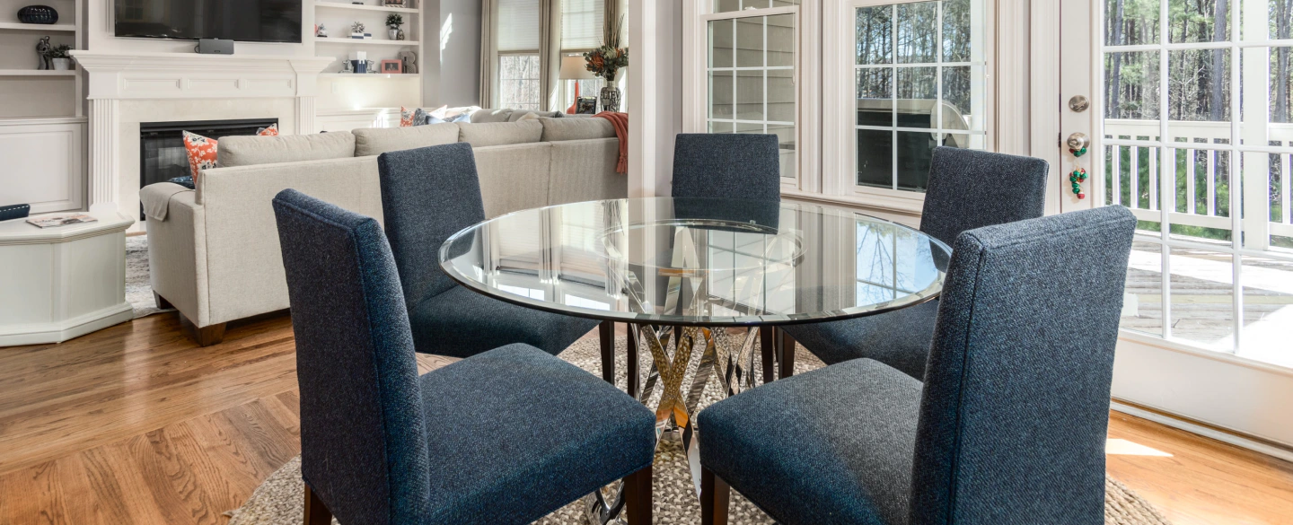 white house with a dining glass table and five dark blue chairs