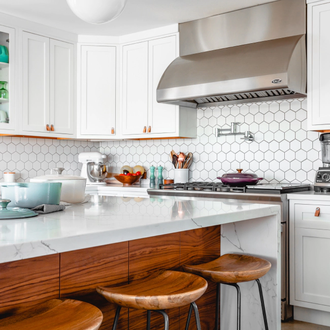 white kitchen with wood chairs a white countertop and a platinum stove