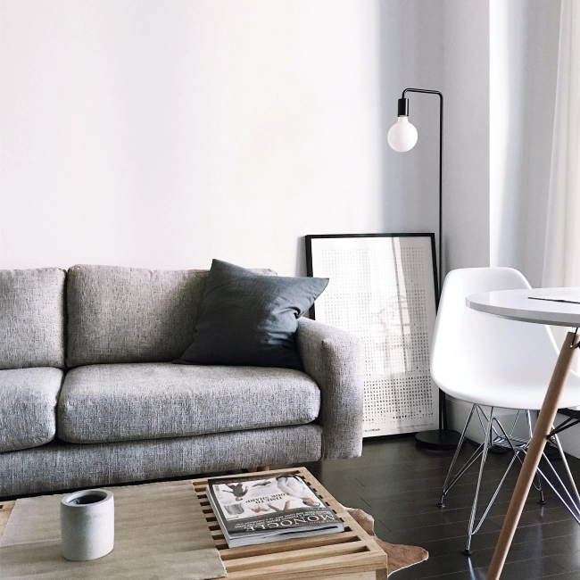 white licing room with a dark grey sofa a white chair and a black lamp