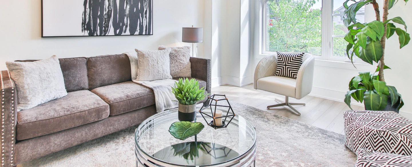 white living room with a greyish brown sofa with white chairs beige and white pillows and some plants